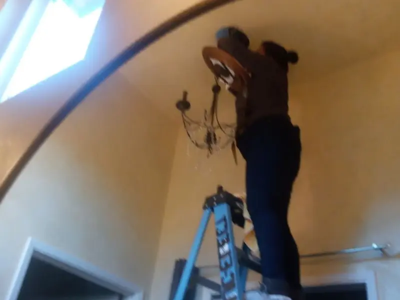 Electrician installing a chandelier in a Georgetown residence